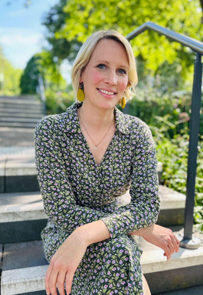 Lisa Messing, Systemische Therapeutin für paare, Einzelpersonen und Familien, sitzt auf Treppe und lächelt in die kamera